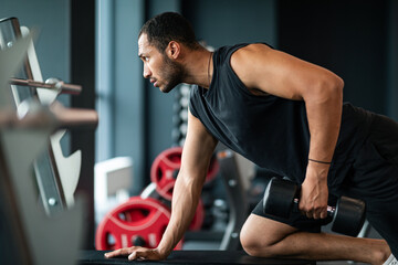 Wall Mural - Young African American Sportsman Training With Dumbbell At Gym Interior