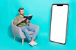canvas print picture Photo of positive curious man sit armchair hold textbook read novel empty space wear pullover isolated blue color background