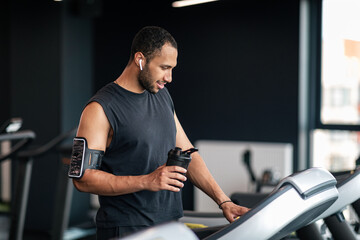 Wall Mural - Jogging Workout. Portrait Of Sporty African American Man Using Treadmill At Gym