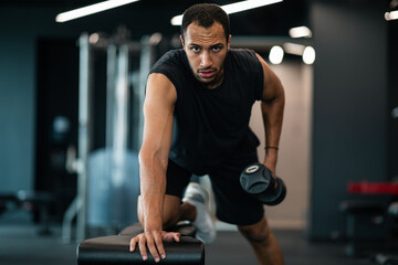 Wall Mural - Muscular african american man doing biceps workout with dumbbell in gym