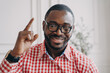 © VK Studio - Smiling African ethnicity male English tutor in glasses raises hand points out with index finger up