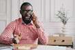© VK Studio - Dissatisfied African American businessman emotionally speaking on smartphone while sitting at desk