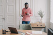 © VK Studio - Young serious african american businessman in casual clothes standing in office with smartphone