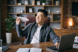 © Prostock-studio - Cheerful handsome middle aged asian businessman play with paper plane at workplace at laptop in home