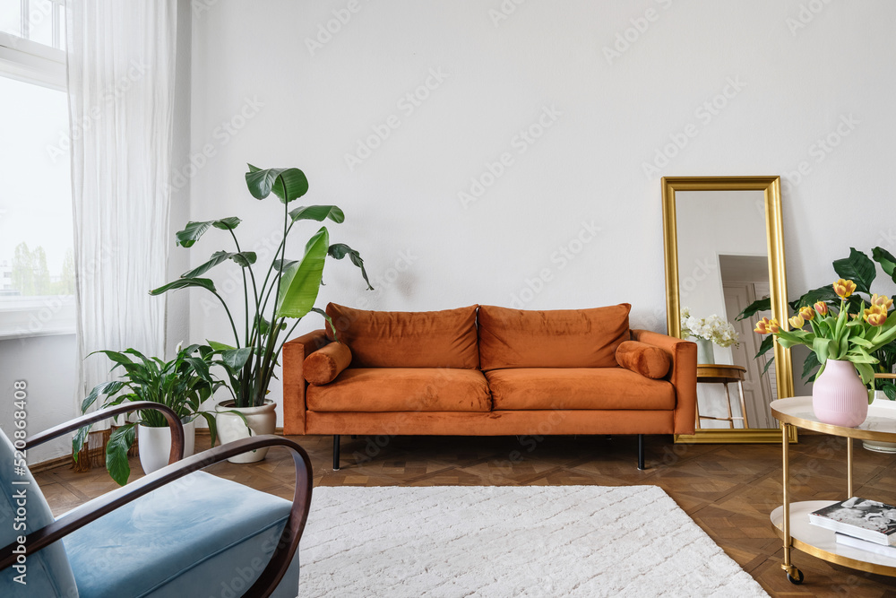 Potted houseplants close to orange couch in retro living room Stock ...