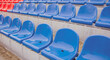 Empty bleacher in sports stadium in rainy weather. Colored wet seats in street stadium. It's raining. Close up.