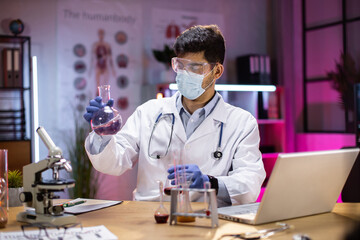 Wall Mural - Positive male arab scientist or medical in lab coat holding test tube with reagent, laboratory glassware containing chemical liquid. Microscope, Biochemistry laboratory research.