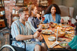© Seventyfour - Portrait of smiling young man in wheelchair enjoying dinner party with friends and holding wineglass, copy space
