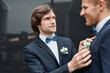 © Seventyfour - Portrait of smiling young man fixing grooms boutonniere during wedding ceremony, same sex marriage concept