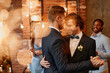 © Seventyfour - Dreamy portrait of young gay couple dancing together during wedding reception with lens flare