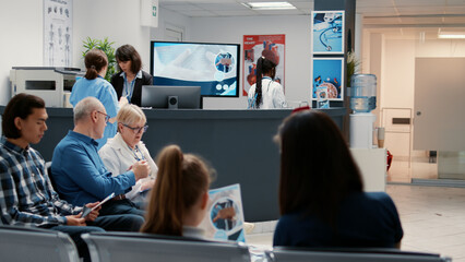 Busy hospital reception with diverse group of patients in waiting room area, having consultation appointment with specialist for healthcare treatment. Reception desk in facility lobby.