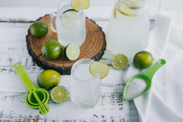 lemonade drink with green lemons or lime on Jar and glass on white background in Latin America	