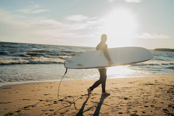 Wall Mural - Surfer man in a wetsuit surfing on a sunny day at sunset