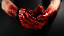 Close-up Of Male Bloody Handcuffed Hands On A Black Background.