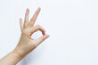 © sirirak - Female hand with ok hand gesture on white cement wall background, sign gesture