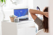 © Юлия Клюева - A young, happy, beautiful freelance business woman sitting in a home office with a laptop and a smartphone in a relaxed pose. A woman works at home.