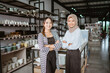 © Odua Images - Two beautiful asian girls smiling while standing with hands crossed in houseware store