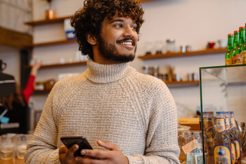 Wall Mural - Portrait of young smiling handsome indian curly man in sweater