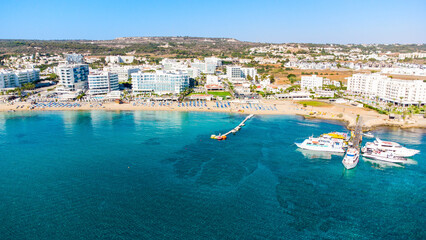 Wall Mural - Aerial bird's eye view of Sunrise beach Fig tree, Protaras, Paralimni, Famagusta, Cyprus.The famous tourist attraction family bay with golden sand, boats, sunbeds, restaurants, water sports from above