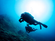 Anonymous Diver Swimming Near Rocky Formation