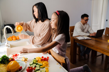 Wall Mural - Happy asian family cooking and working on laptop at home