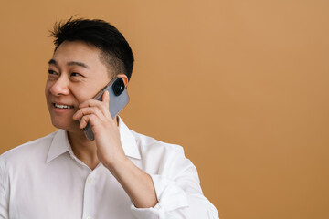 Wall Mural - Brunette adult asian man laughing and talking on cellphone