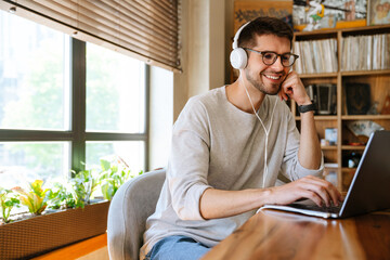 White young man smiling while working with laptop at office