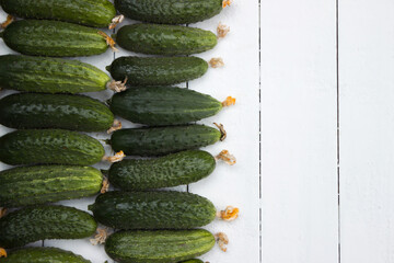 Plucked ripe cucumbers, white wooden background. Green healthy vegetables, top view