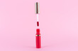 Lipstick and applicator wand on pastel pink background. Liquid lip stick red lip gloss open tube. Makeup cosmetic product. Top view, flat lay, copy space