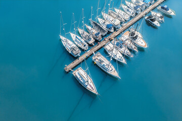 Top view from drone of sailboats and various speed boats in dock. Aerial view of luxure yachts and motorboats moored in a port with clear blue water in summer. Pula, Croatia