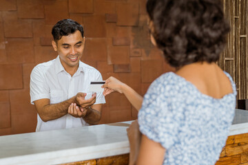 Wall Mural - The receptionist accepts credit card payments from female guests in the hotel lobby