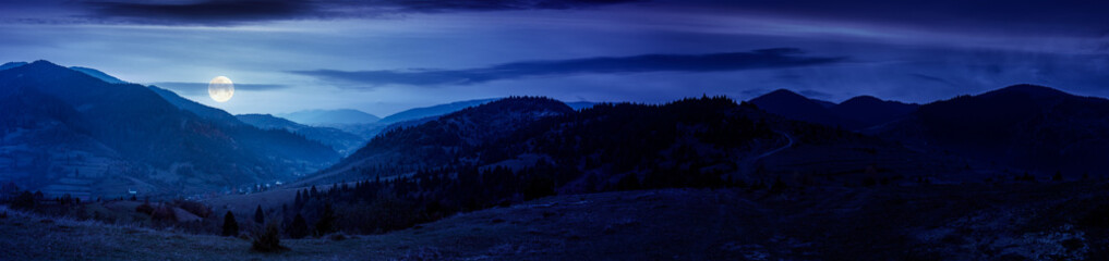 Wall Mural - panorama of countryside landscape at night. grassy pasture meadows and forested hills in autumn. mou