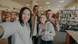 © silverkblack - Point of view of international student group have fun smiling and taking selfie photos on smartphone camera at university library indoors