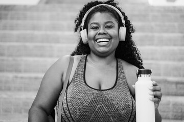 Wall Mural - Sport curvy black woman listening music with headphones - Focus on face - Black and white editing