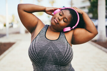 Wall Mural - Curvy african woman stretching during workout routine outdoor - Focus on face