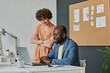© AnnaStills - Two colleagues working over presentation online on laptop at table at modern office