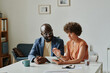 © AnnaStills - Young businesswoman discussing online project on digital tablet together with her colleague at table at office