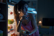 © StockPhotoPro - Hungry woman eating sweets at night