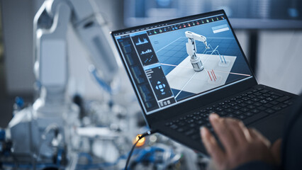 black female engineer using laptop for programming robotic arm at the modern assembling factory. new