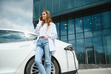 girl charging electro car at the electric gas station