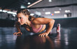 Determined female training during pushing up exercises activity and healthy lifestyle, muscular fit girl practice plank exercises toning physical strength during cardio workout in sportive gym