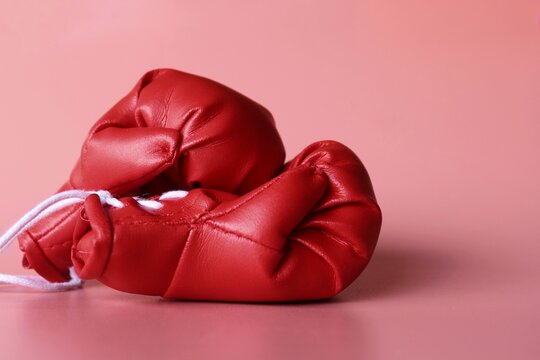 Close up image of red boxing gloves on pink background. Sports concept