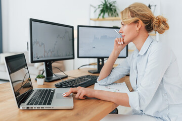 Side view. Female stock broker in formal wear is working in the office