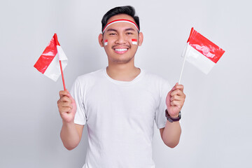 Wall Mural - Portrait of Excited young Asian man celebrating indonesian independence day on 17 august and holding indonesian flag isolated on white background studio portrait