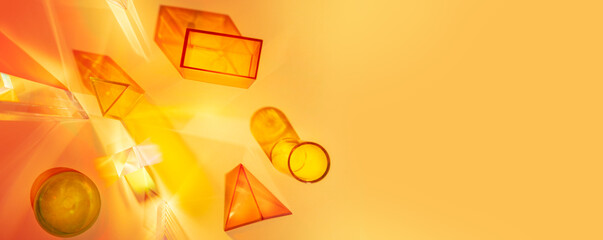 Wall Mural - Abstract scene with geometric shapes and light rays on an orange-yellow background. Set of colored transparent geometric forms.