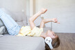 © Julija - kid girl lying upside down on couch at home, listening music in earphones.