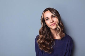 Wall Mural - Portrait of a happy young business woman posing against a gray wall.