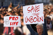 Protesters Holding Signs Save The Unborn, Pro Life. People With Placards Against Abortion Rights At Protest Rally Demonstration. Concept Image.