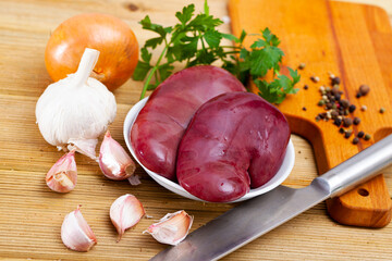 Wall Mural - Raw meat food, fresh pork kidneys with condiments on wooden table