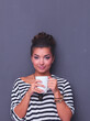 © lenets_tan - Young woman standing with cup, isolated on gray background. Young woman